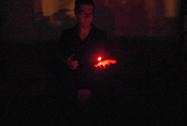 Person im Dunkeln mit einem Licht über der Hand